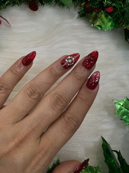 A single-hand shot to show the detail of the diamond snowflake accent nail against the glittery red.