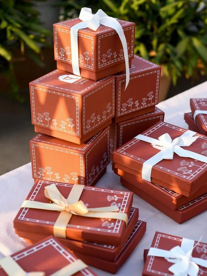 A stack of beautifully packaged gift boxes from Patrika Gift Shop, ready to be shared. The soft, natural light highlights the delicate design and ribbon details, evoking a sense of anticipation and celebration.