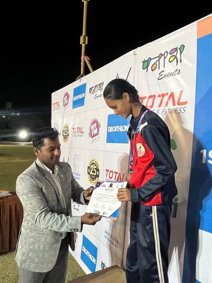 An athlete receives her certificate and medal on the podium, a moment of recognition for her hard work.