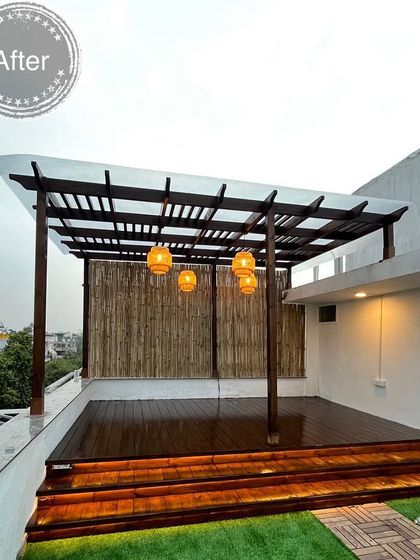 The final result of a rooftop transformation project, featuring a covered seating area under a new pergola, a polished wooden deck, and a lush green lawn space.