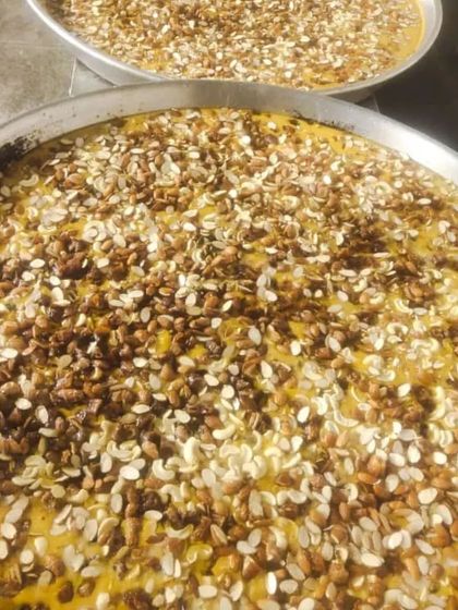 Two large platters of a rich, yellow sweet dish, possibly Shahi Tukda, topped with a generous amount of nuts. Perfect for serving a large crowd.
