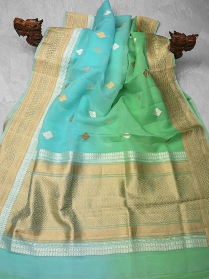 A lovely organza-cotton blend saree in shades of aqua and lime green with a gold border. The fabric is lightweight and has a subtle sheen, making it perfect for semi-formal day events.