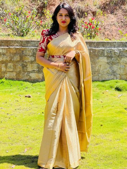 A full-length shot of the client in her beige saree and red brocade blouse, a classic and elegant combination.