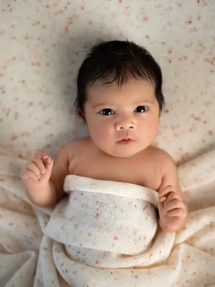 A captivating stare from a newborn with beautiful, dark eyes. This simple portrait with a speckled blanket keeps the focus entirely on the baby.