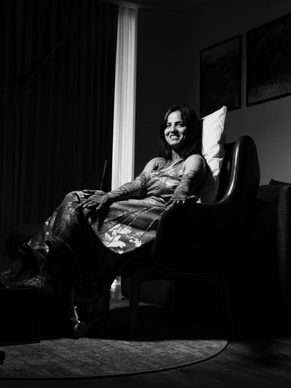 A classic black and white portrait of the bride seated in a chair. The dramatic lighting creates a timeless and sophisticated image.