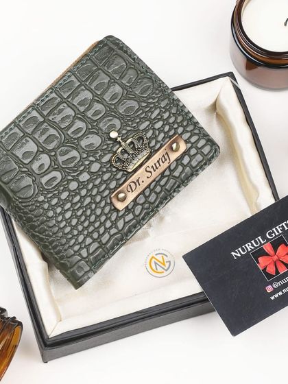 A green crocodile leather wallet, personalized for 'Dr. Suraj' with a crown charm.