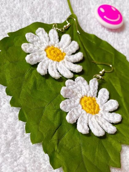 A pair of delicate, handmade crochet daisy earrings. These are a light and fun accessory, perfect for adding a floral touch to any outfit.
