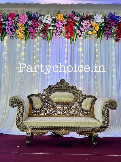 An elegant stage with a white curtain backdrop and fairy lights, topped with a colorful floral runner. This versatile setup is perfect for a half saree or puberty ceremony.