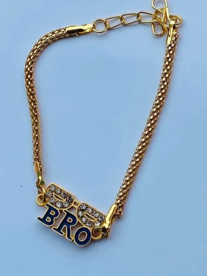 A close-up of the "BRO" rakhi featuring cool sunglasses. The sparkling stones and dark enamel make this a standout piece.