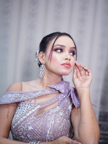 A close-up portrait highlighting the intricate silver beadwork and the one-shoulder design.