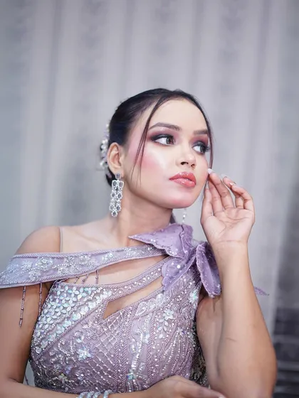 A close-up portrait highlighting the intricate silver beadwork and the one-shoulder design.