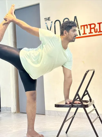 A side profile demonstrating the use of a chair in Natarajasana. You can clearly see how the chair helps to maintain balance while working on lifting the leg and opening the chest.