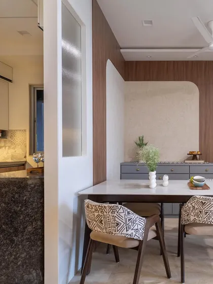 A closer look at the dining area in 'House in the Hills', where modern chairs with tribal-print fabric add a unique touch to the wooden dining set.