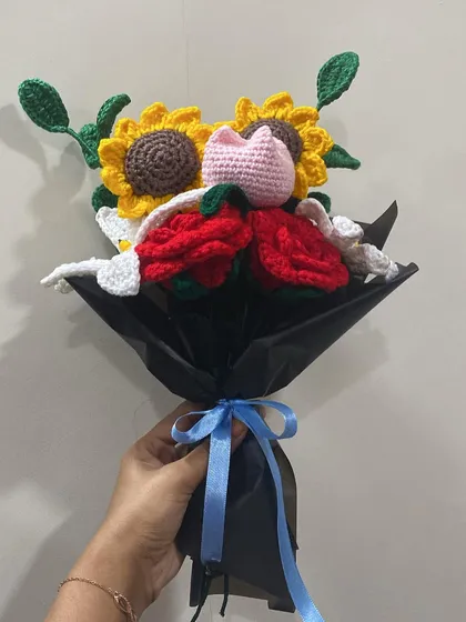 Holding the mixed bouquet of sunflowers, roses, and lilies. The blue ribbon adds a nice pop of color against the black wrapping.