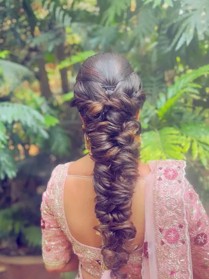 A voluminous and textured pull through braid that creates a modern, almost fairytale look. This style is perfect for a reception or engagement, adding incredible dimension and detail to the hair.