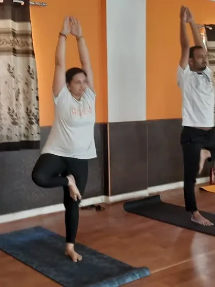 A mixed group of students practicing Vrikshasana (Tree Pose) together.