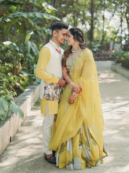 A full-length shot showing the couple's coordinated Haldi outfits. The bride's makeup is kept light and fresh to match the relaxed and happy vibe of the event.