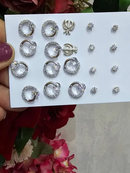 A display card of our minimal small screw earrings, including sparkling hoops and Khanda symbols.