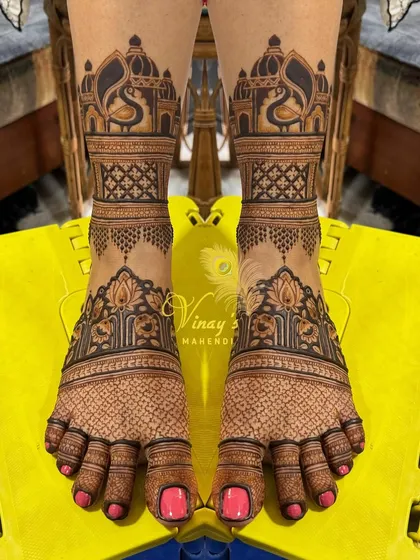 Symmetrical bridal feet mehndi featuring palace architecture and peacocks. The detailed jaal work on the toes adds another layer of intricacy.