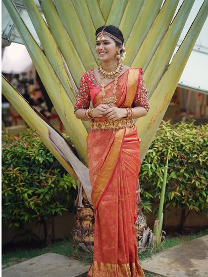A full view of the bride against a natural backdrop, highlighting how our jewellery stands out. The Vaddanam and layered necklaces are key features of this rental set.
