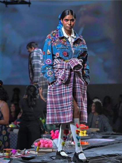 A model on the runway at Lakme Fashion Week. I styled her hair with a simple side braid and a blue ribbon accessory, adding a touch of color and detail to complement the embroidered denim and plaid outfit.