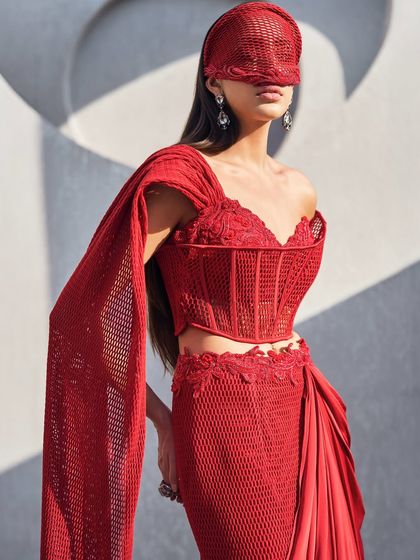 A closer look at the sheer mesh corset of the red sari, where structure and softness meet. The attached drape flows like refracted light, designed to leave an unforgettable impression.