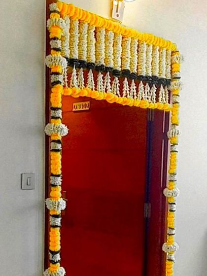 A front door flower decoration using yellow, black, and white artificial flower garlands. This unique color combination offers a modern twist on a traditional design.