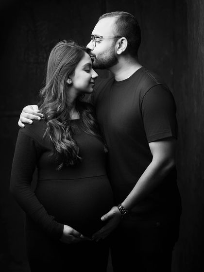 An intimate and emotional black and white portrait. The simple gesture of a kiss on the forehead speaks volumes, and the moody lighting adds a layer of depth and tenderness.