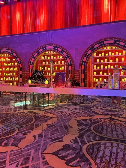 The stunning bar setup for the red Sangeet, with arched back-panels filled with glowing candles, creating a warm and inviting yet dramatic focal point.