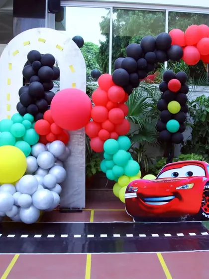 A close-up of the Lightning McQueen character prop and the balloon arch. The details, like the smoke-like white balloons, add a fun touch to the racing theme.