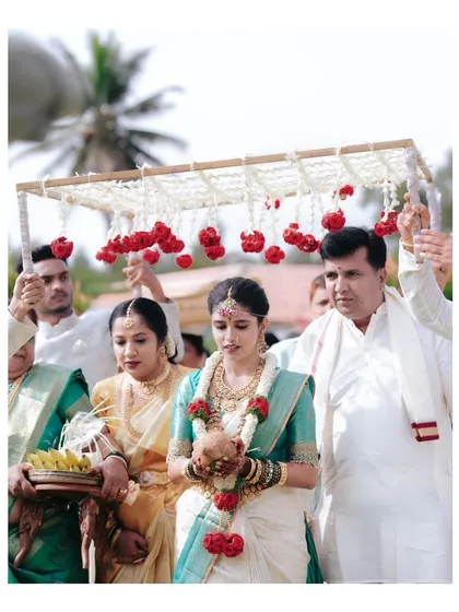 The bride's grand entrance, a significant and beautiful tradition in South Indian weddings, as she is escorted by her family under a floral canopy.