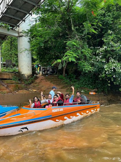 A group waving from a speedboat in Honnavara.