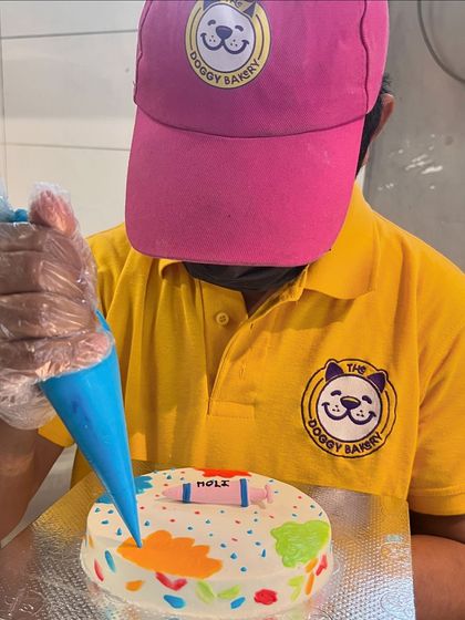 Our baker decorates a special Holi-themed cake, complete with a "pichkari" and splashes of natural color.