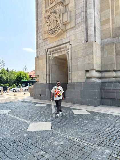 Exploring Bucharest, Romania. For this day out, I chose a graphic print t-shirt paired with dark trousers and white sneakers for a comfortable and modern tourist look.