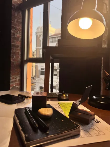 A desk at The Loft, where our material truths are on display. The raw brick wall, the view of the old city, the simple wooden desk. These aren't finishes; they are beginnings.