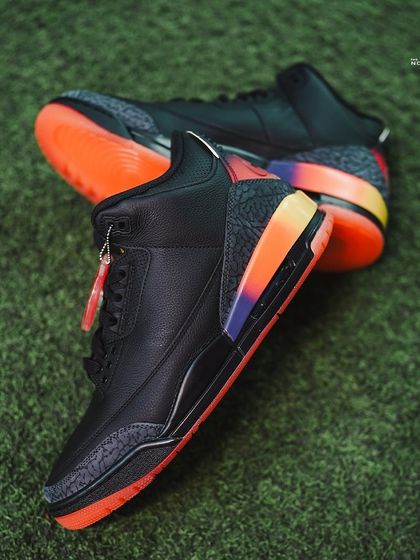 A top-down view of the Jordan 3 J Balvin 'Rio' on a turf background, showing off the black leather upper and the striking gradient midsole.