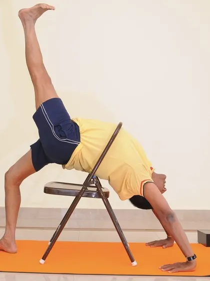 A variation of Adho Mukha Vrksasana (Handstand) using a chair. The chair supports the pelvis, allowing you to work on shoulder stability and spinal extension.
