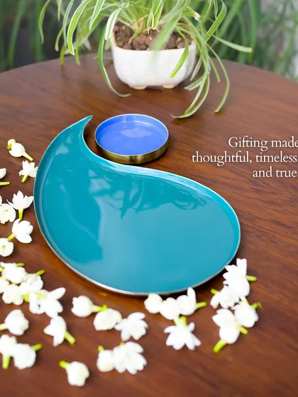 Gifting made thoughtful, timeless, and true. This paisley-shaped tray in a beautiful teal, styled simply on a wooden table, shows how our pieces from 'The Spirit of Celebration' can make a quiet, elegant statement.