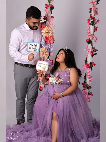 Announcing their new roles as "Mommy to be" and "Daddy to be" with cute props. The floral swing adds a playful and romantic touch to this fun shot.