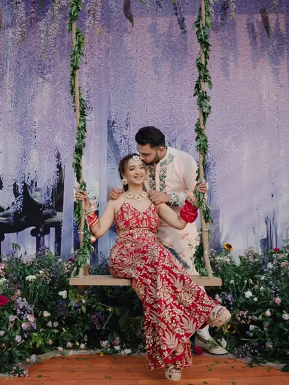 The groom shares a tender moment with his bride on the swing during their Mehendi. His gentle kiss on her forehead is a perfect capture of their affection.
