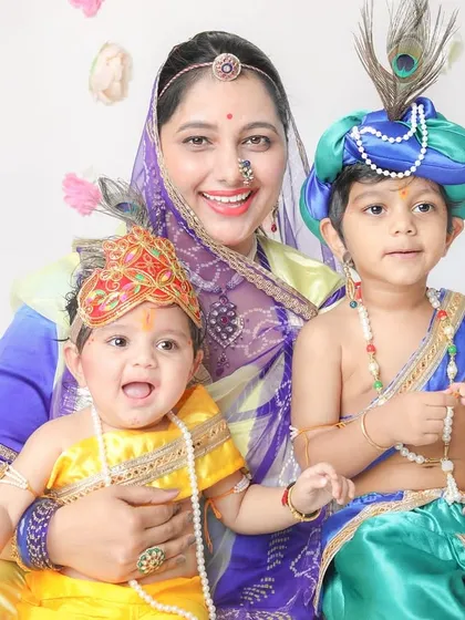 A beautiful portrait of a mother with her two boys, one as Krishna and the other as Balram, against a clean, simple backdrop.