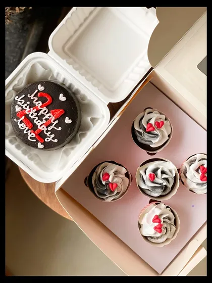 A striking black, white, and red themed combo for a 21st birthday. The dark chocolate bento cake is paired with five cupcakes that have swirled black and white frosting and tiny red hearts.