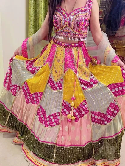 A vibrant multi-color patchwork lehenga on display, featuring panels of yellow, pink, and green with mirror work, perfect for a Mehendi or Sangeet.