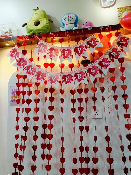 A lovely anniversary decoration with a 'Happy Anniversary' banner and curtains made of red paper hearts.