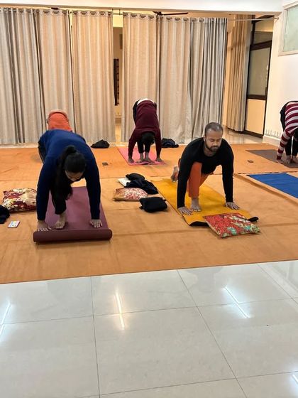 A group practices Ashwa Sanchalanasana as part of the Surya Kriya sequence, building strength and flexibility.