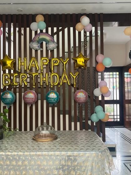 A simple and sweet pastel rainbow theme for a home birthday party, using foil balloons and small balloon clusters.