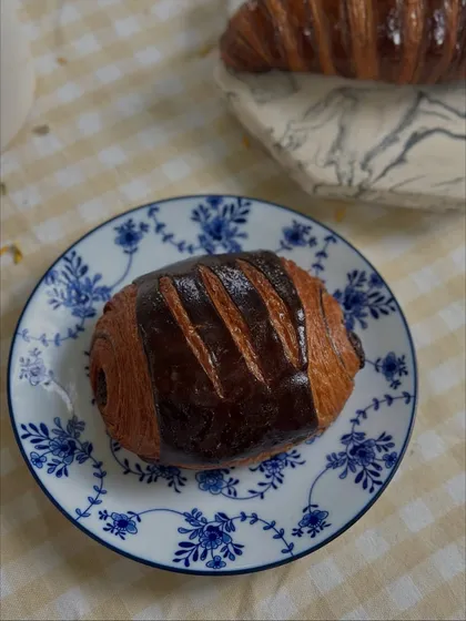 A classic Pain au Chocolat, with its distinct shape and rich dark chocolate filling. A perfect companion to a cup of coffee.