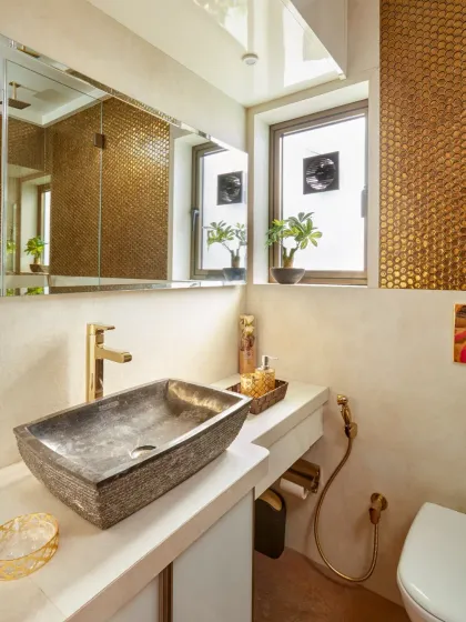 This powder room is all about warmth and texture. The golden penny-round mosaic tiles create a stunning accent wall, perfectly complemented by a natural stone vessel sink and brushed gold fixtures.