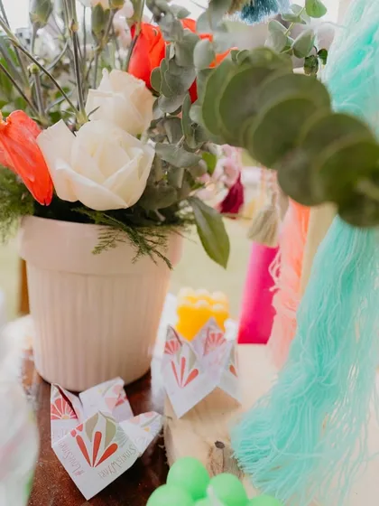 A close-up of a table centerpiece featuring personalized origami and colorful tassels, showcasing our commitment to weaving the theme into every detail.