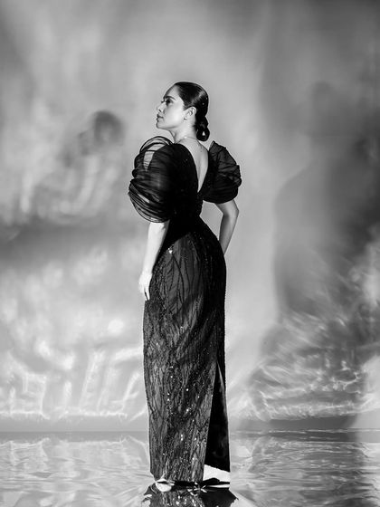 A full-length back profile, showcasing the elegant silhouette of the gown against a beautifully textured, ethereal background.